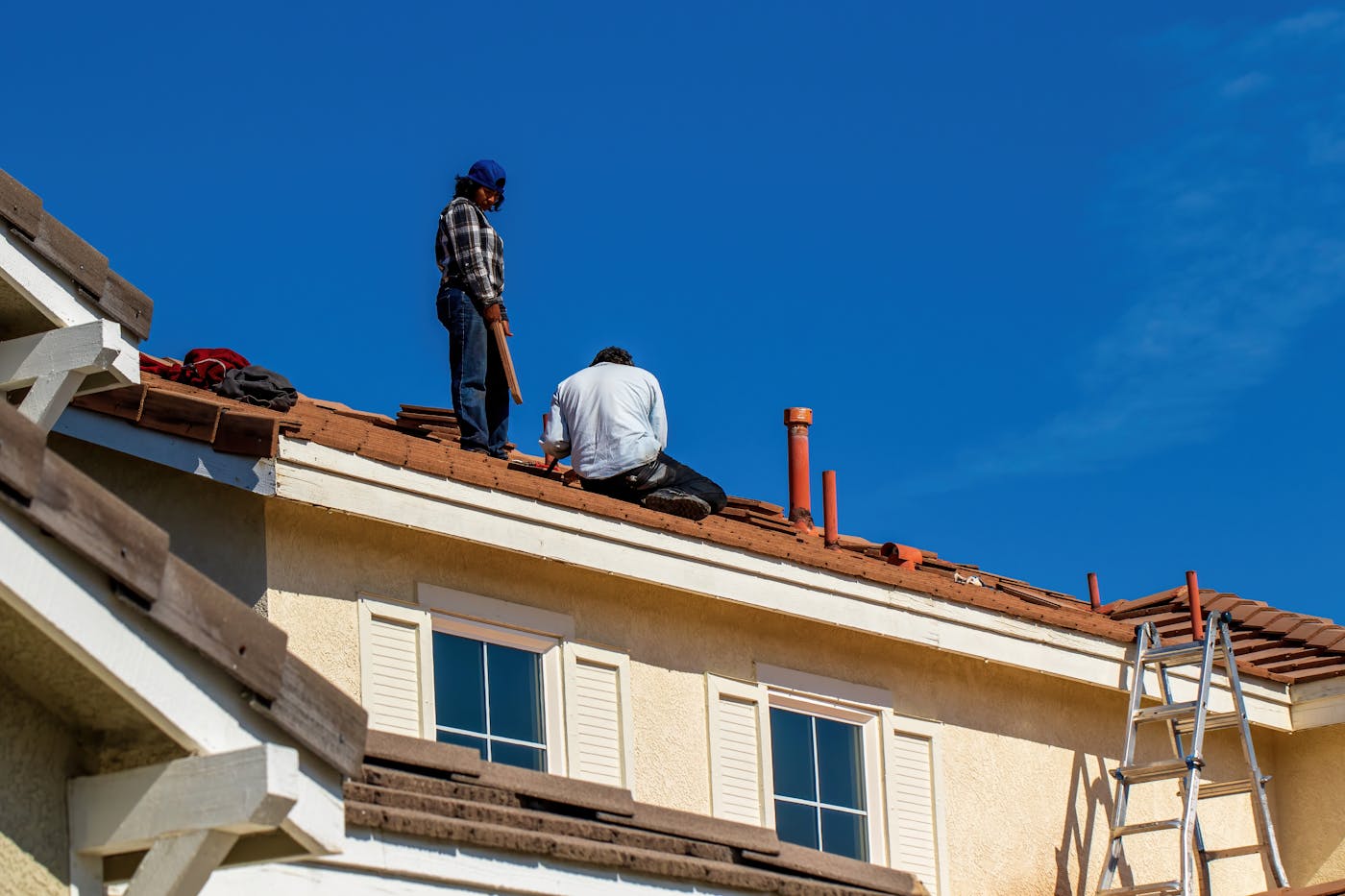 Builders fixing a tiled roof from below, showing the kind of roofline access needed for gutter repair